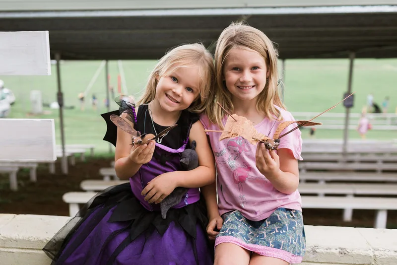 Two young female children holding hand made bats at Bat Night 2021