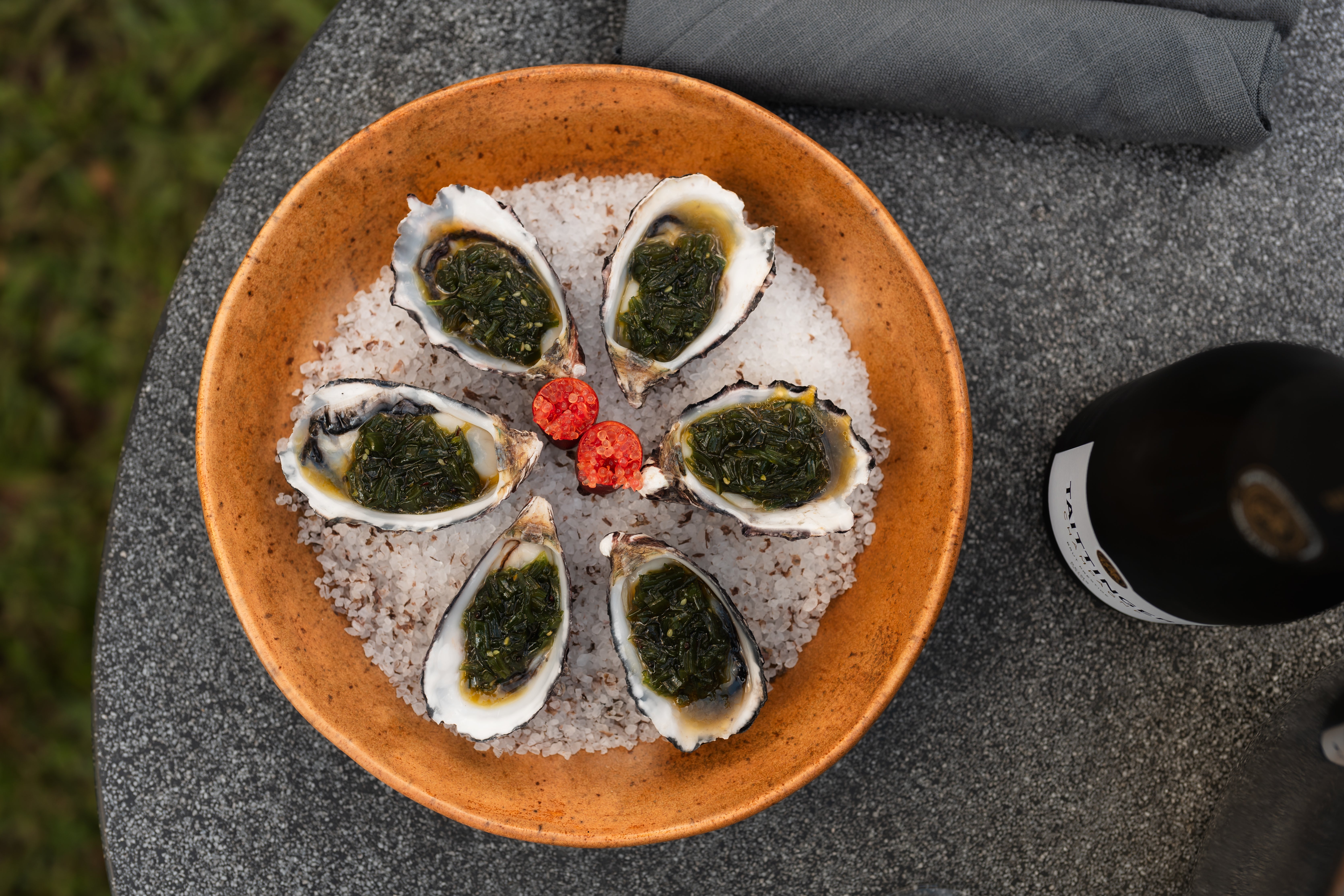 Plate of six oysters with a bottle of champagne beside the plate