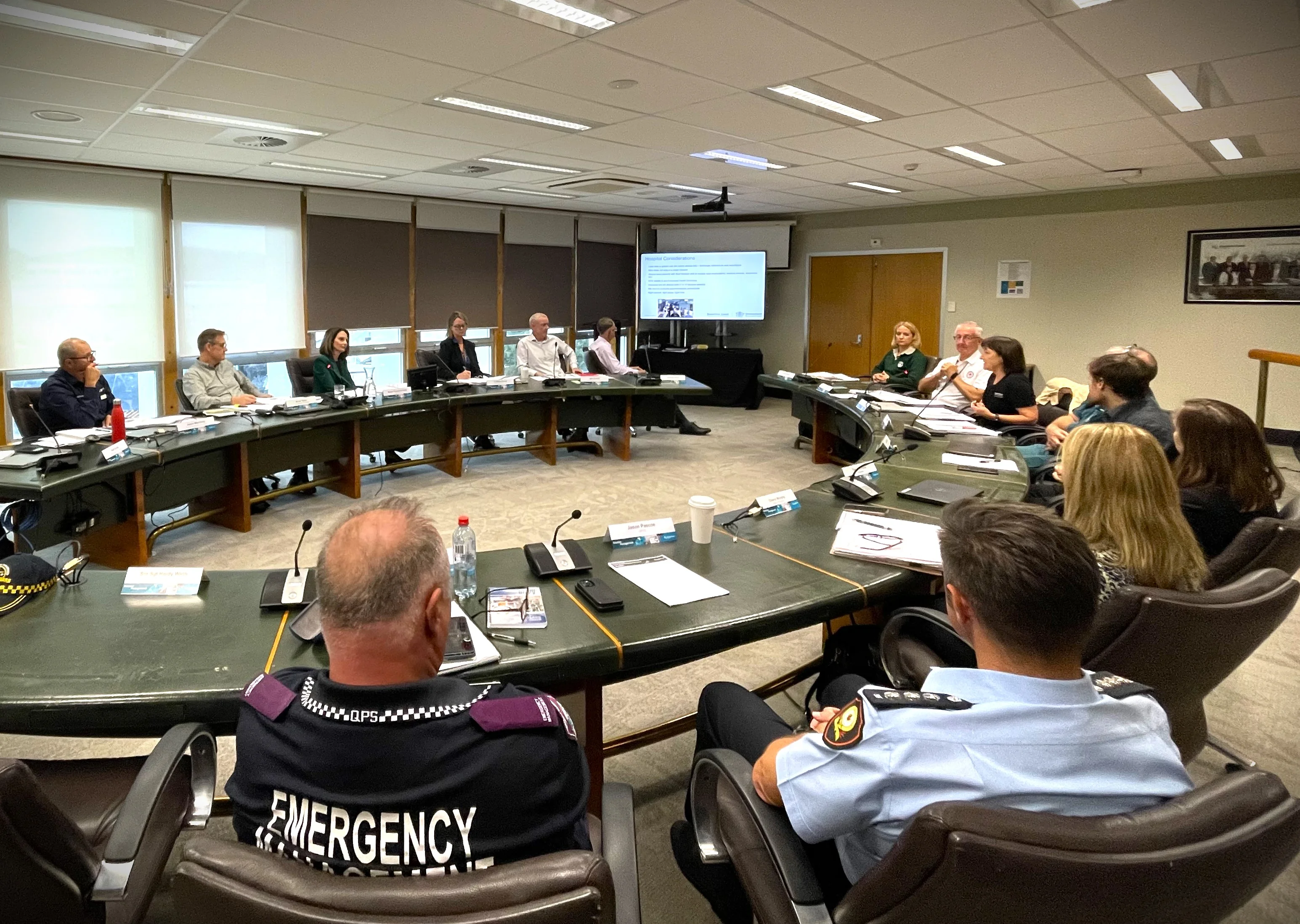 Sunshine Coast Council Disaster and Emergency leaders in Council's large meeting room, sit around a large desk and present reports from their emergency organisations.