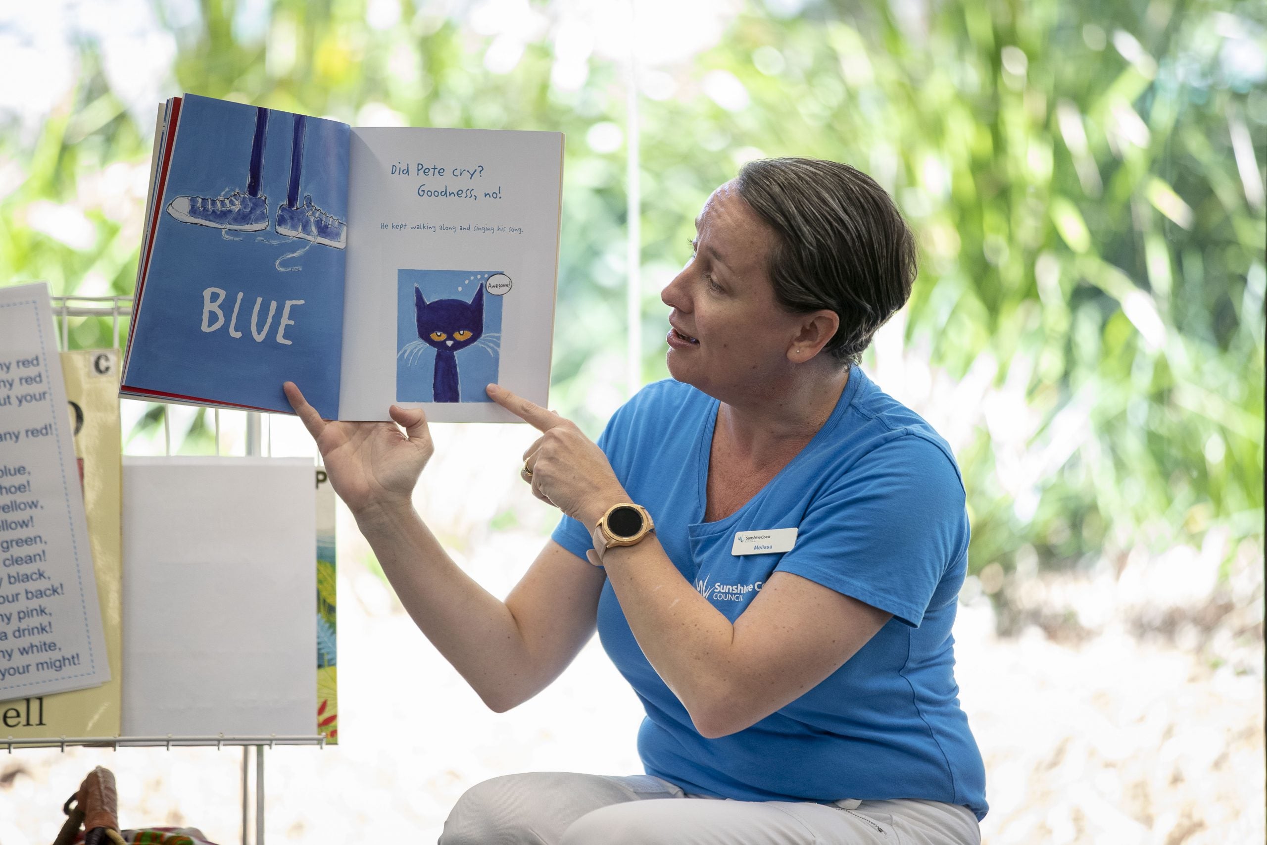 A Librarian holding up a book and pointing to an image in the book.