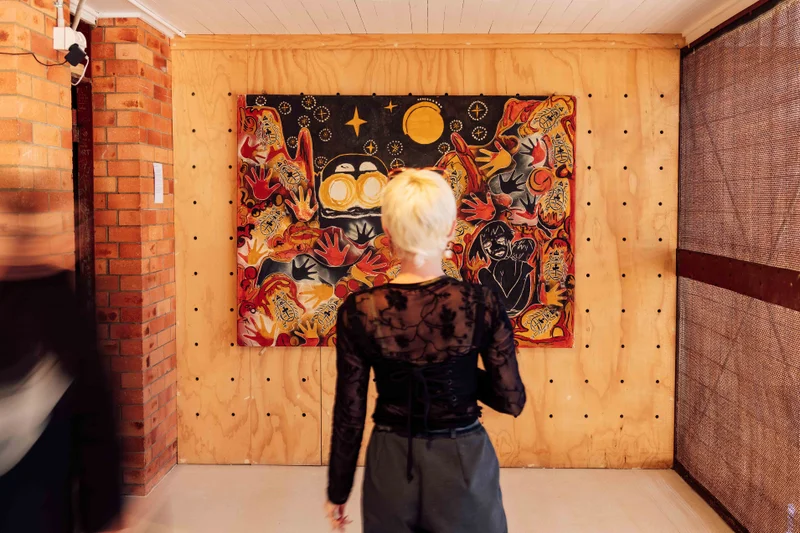 A woman looks at a painting by Aunty Hope at INARI