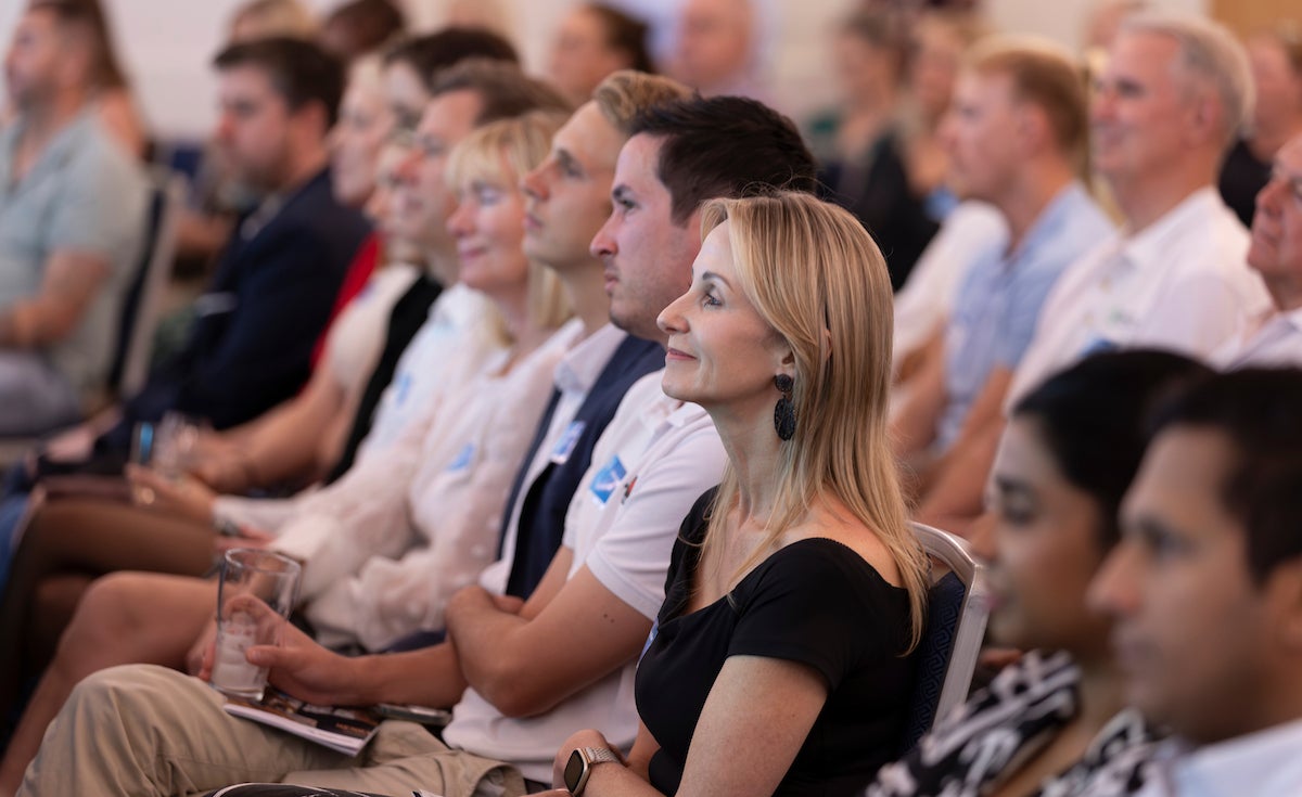 People sitting as an audience looking towards a speaker on stage