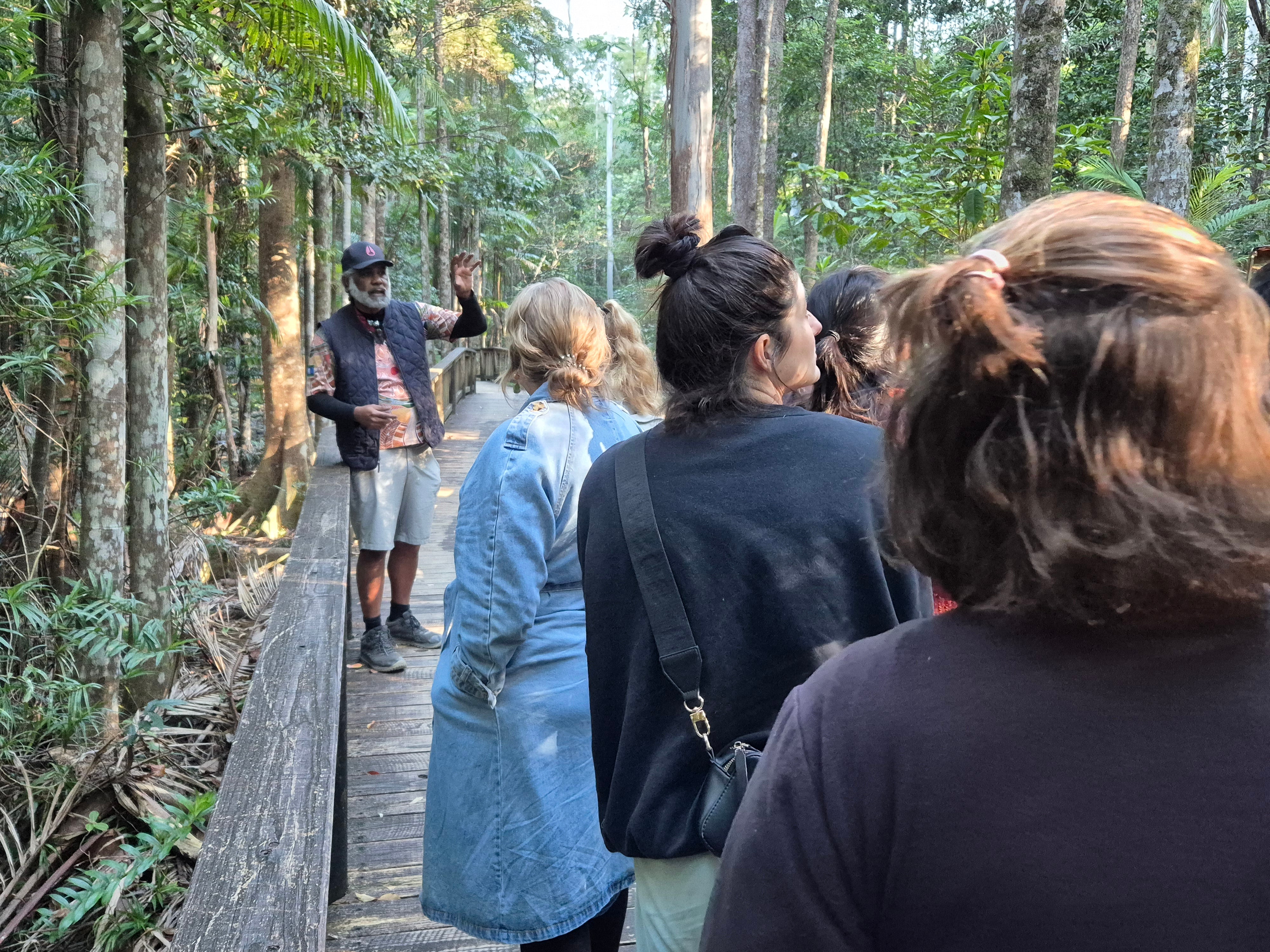 Lyndon Davis leads a First Nations cultural tour along a boardwalk in a forest.