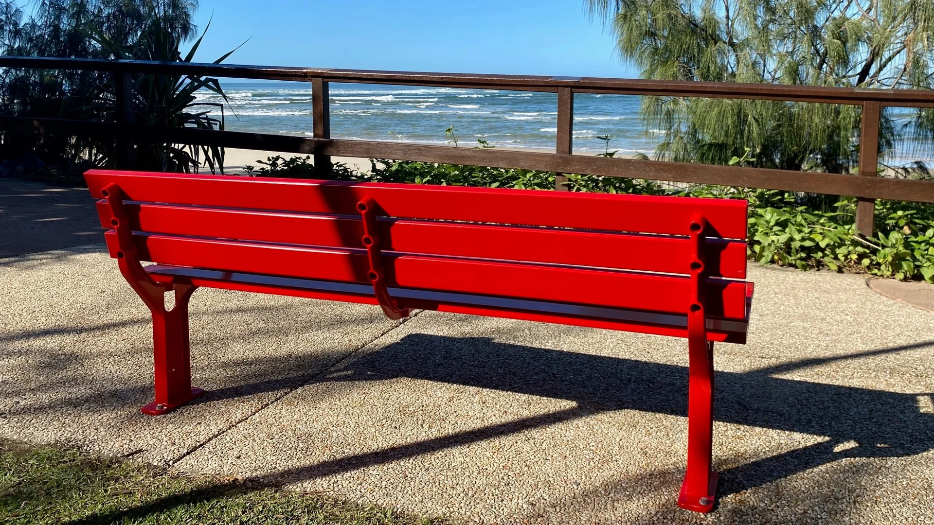 Red park bench looking out to the ocean.
