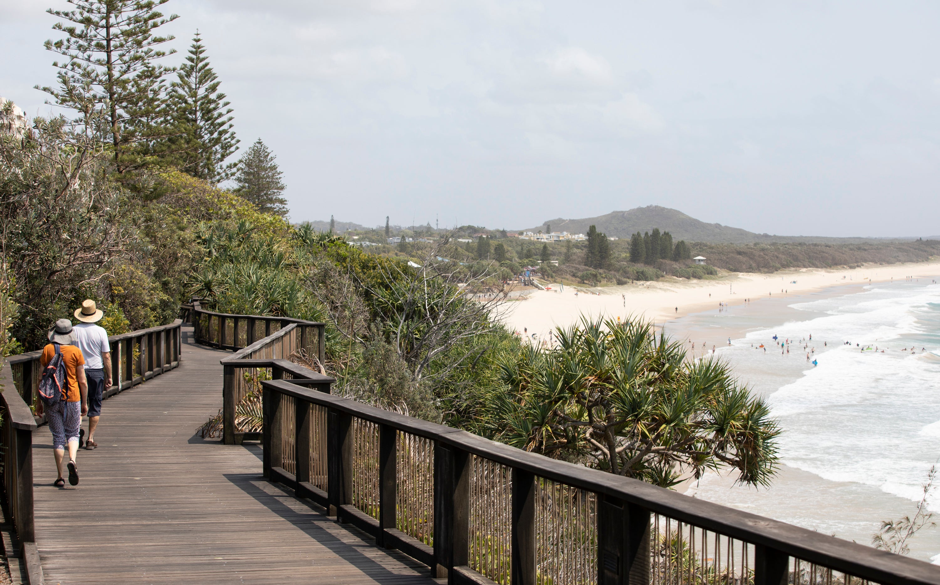 People walk along the coastal boardwalk at Coolum Beach.