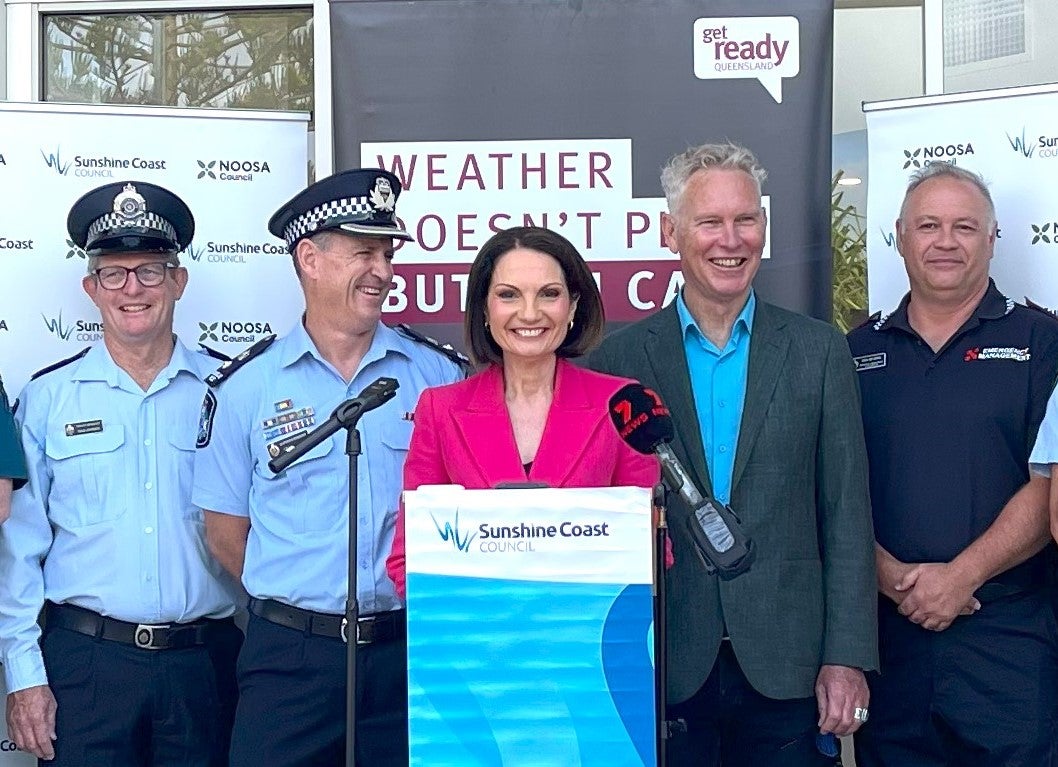 Mayor Natoli and Frank Wilkie are smiling as they stand behind a podium for the Get Ready Week launch. They are flanked by smiling emergency service personnel in uniform.
