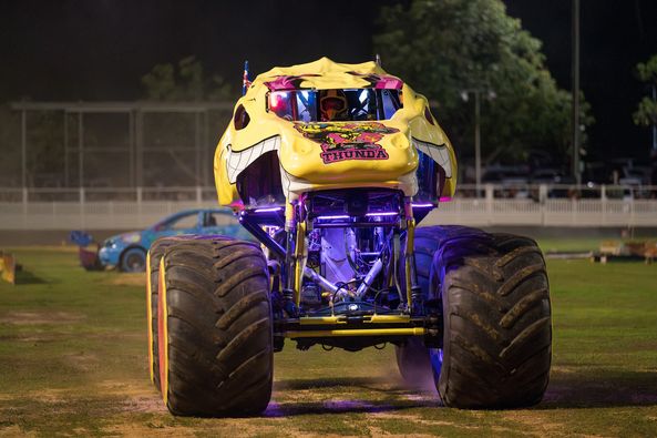 A front on view of a yellow and purple monster truck.