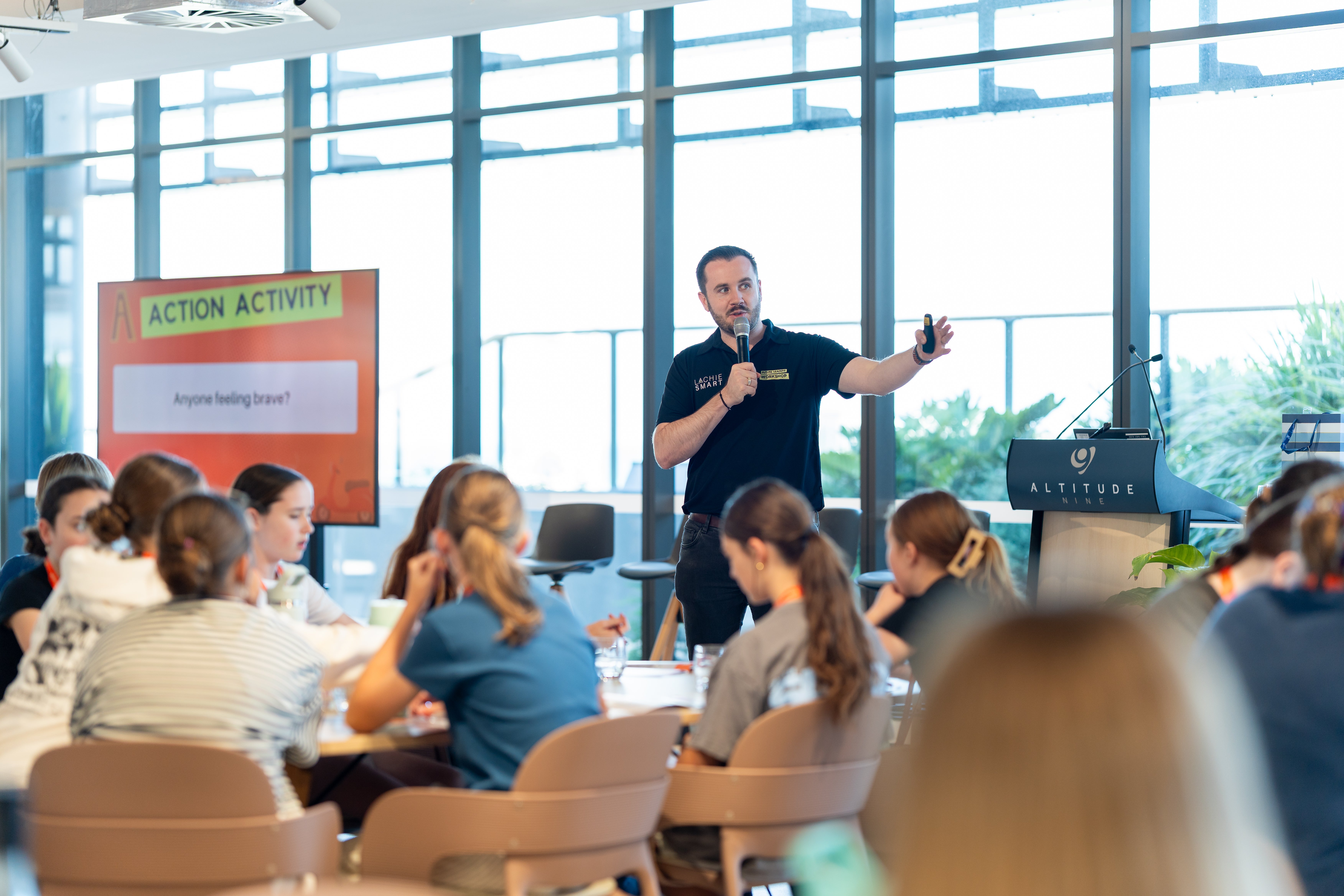 Lachie Smart presenting to students at Masterclass One at venue Altitude Nine (floor to ceiling windows behind him)