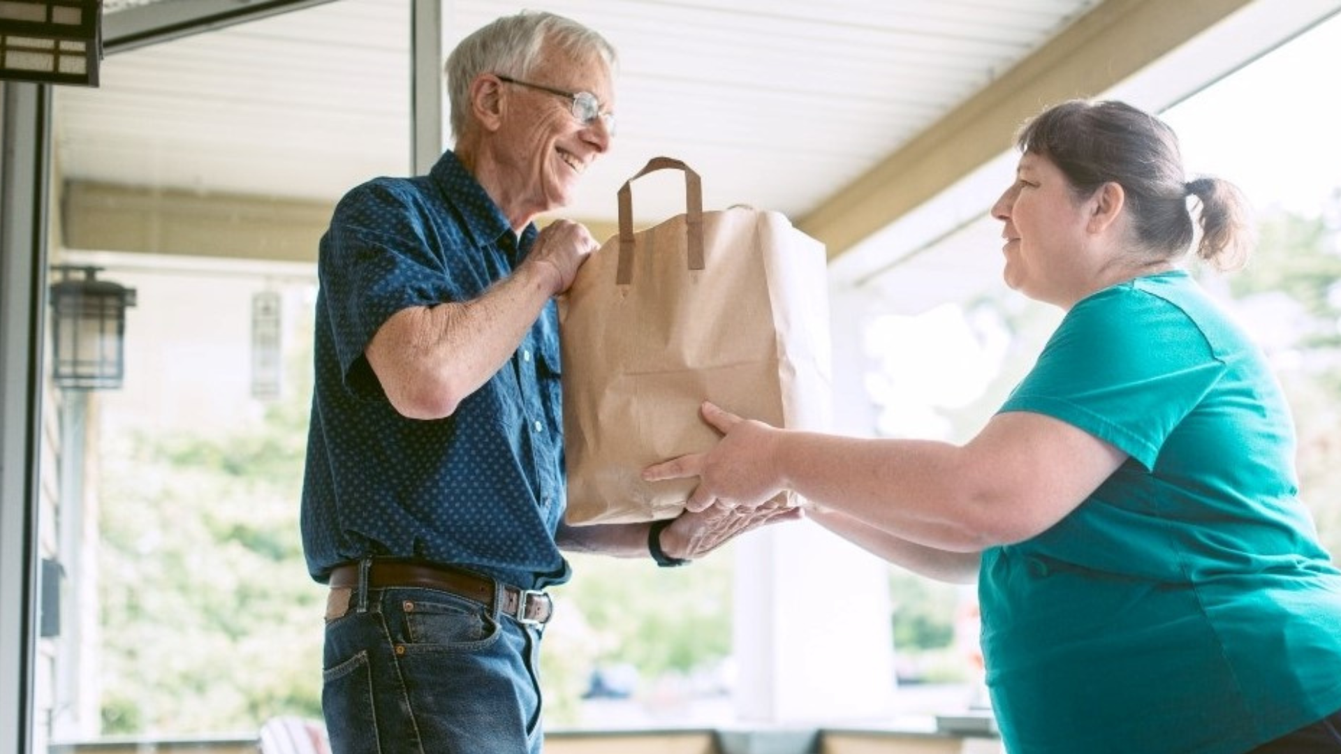 Lady delivering groceries to a man at his front door