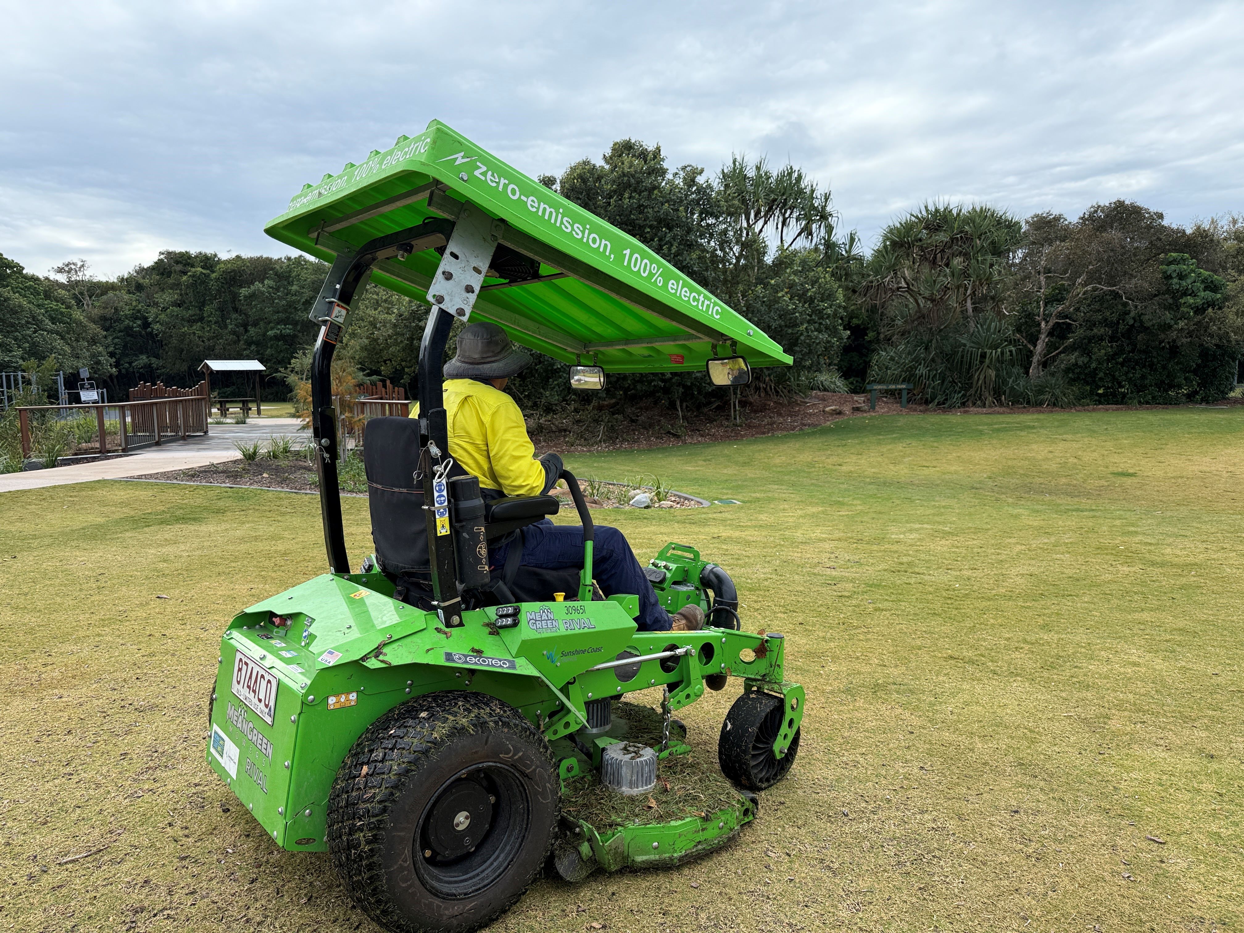 A parks and garden worker in an electric ride-on mower.